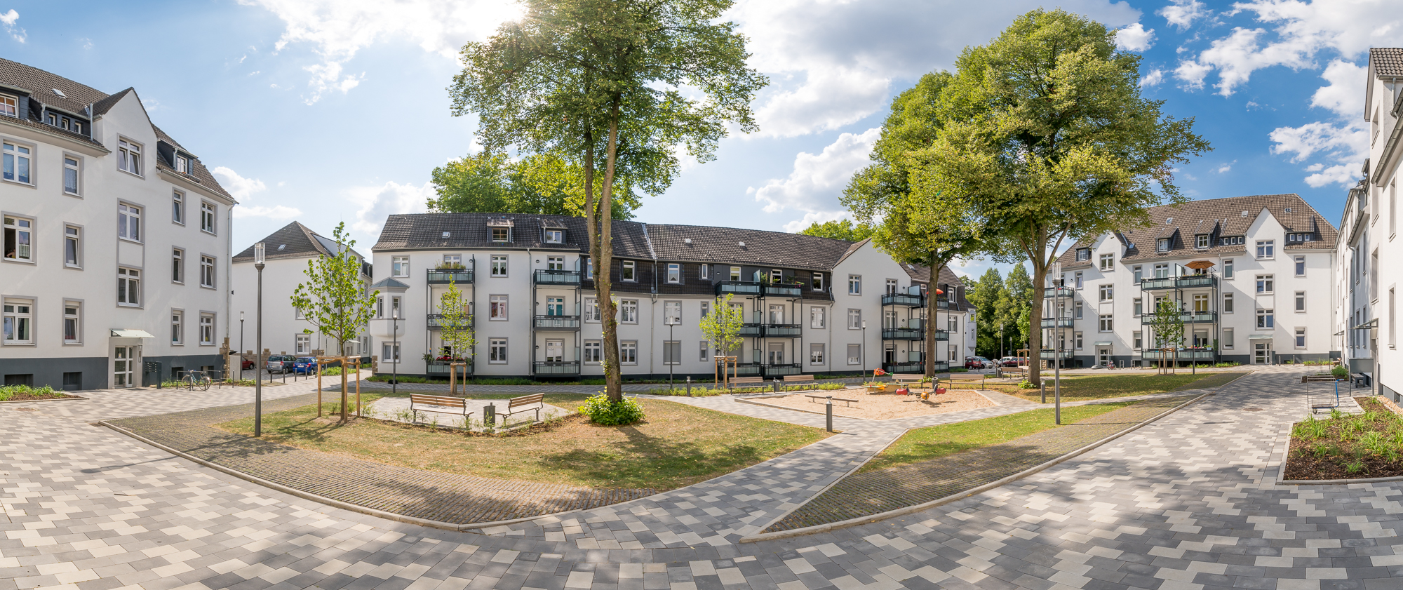 Eltingviertel, Dortmund. Mehrfamilienhäuser umgeben Spielplatz bei sonnigem Wetter. Eltingviertel, Dortmund. Mehrfamilienhäuser umgeben Spielplatz bei sonnigem Wetter.