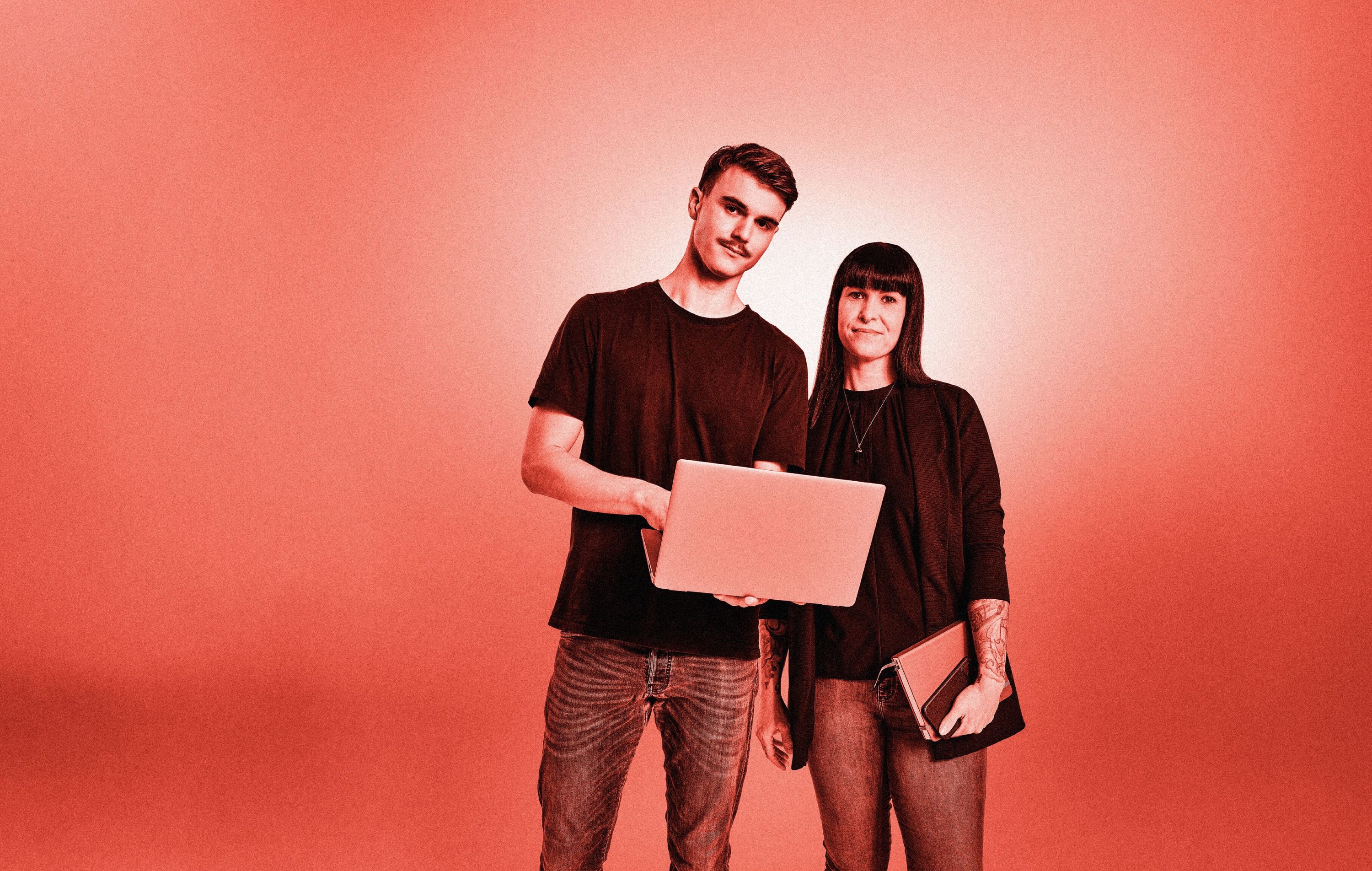 Zwei Studenten posieren mit Laptop und Notizblock. Roter Filter über dem gesamten Bild.