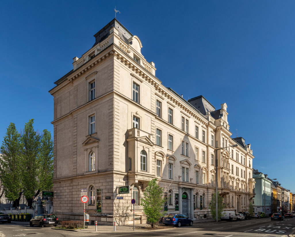 Historisches Gebäude an einer Straßenecke bei sonnigem Wetter.