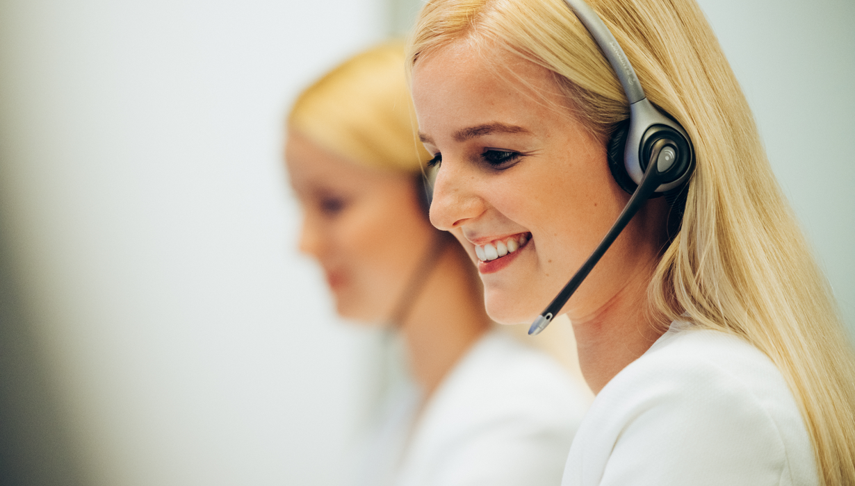 Zwei Frauen mit Headsets arbeiten in einem modernen Büro.