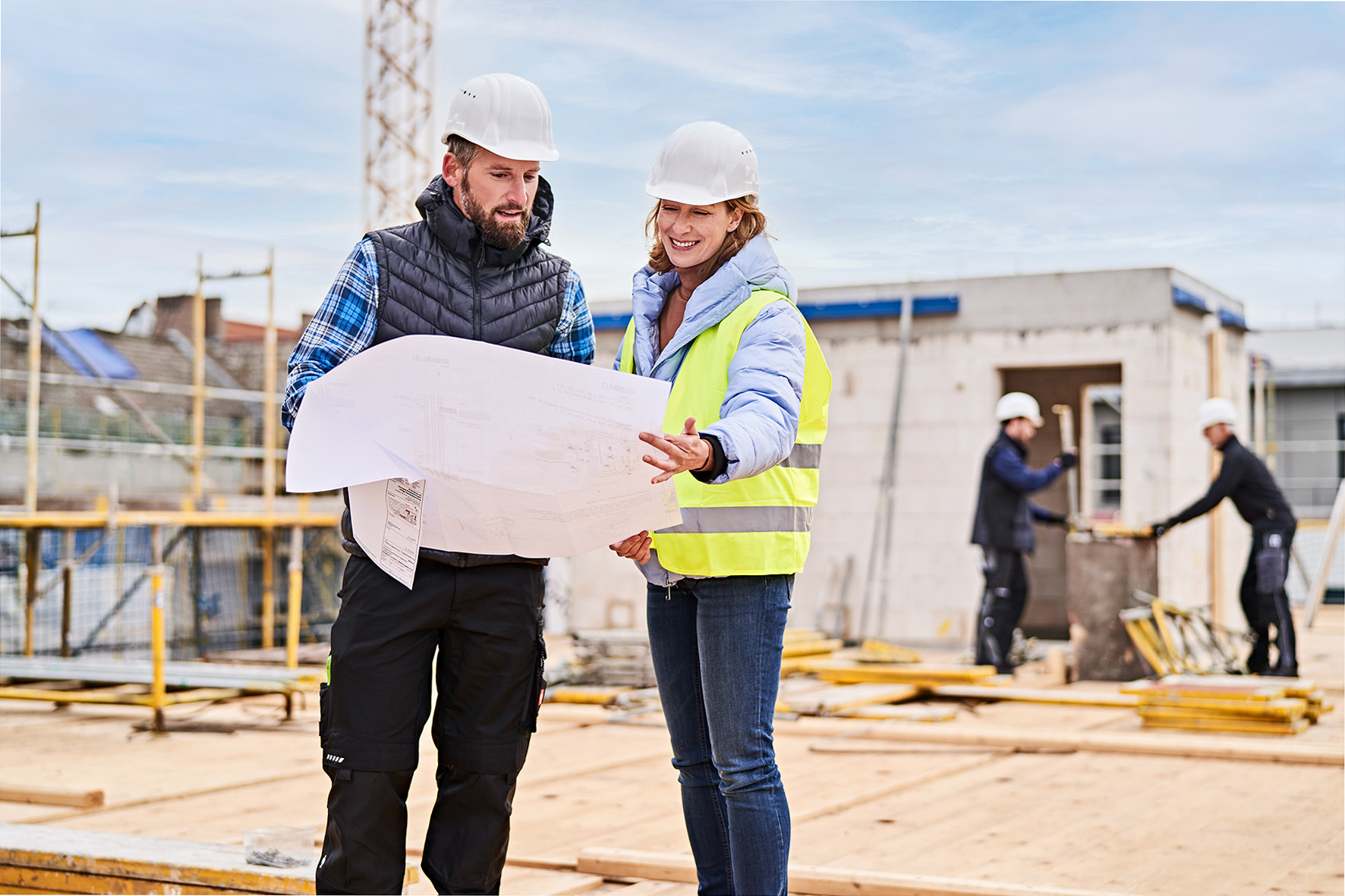 Zwei Bauarbeiter lesen Bauplan auf einer Baustelle.