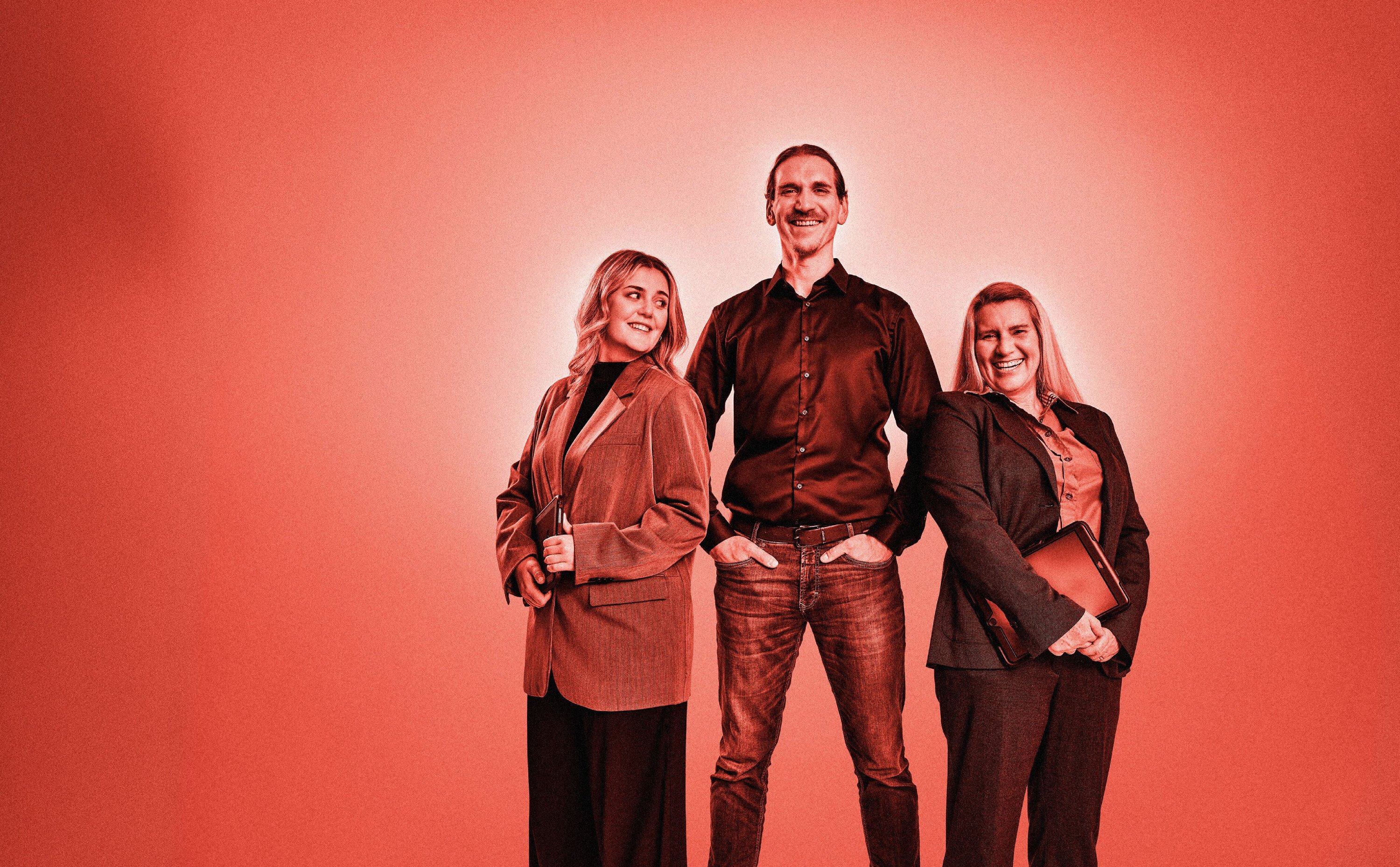 Drei Mitarbeitenden posieren für die Kamera. Roter Filter über dem gesamten Bild.