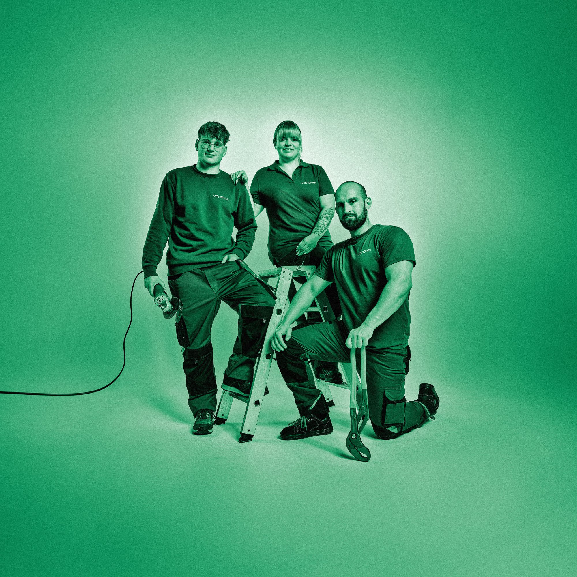 Drei Mitarbeitenden posieren mit Werkzeug. Grüner Filter über dem gesamten Bild.